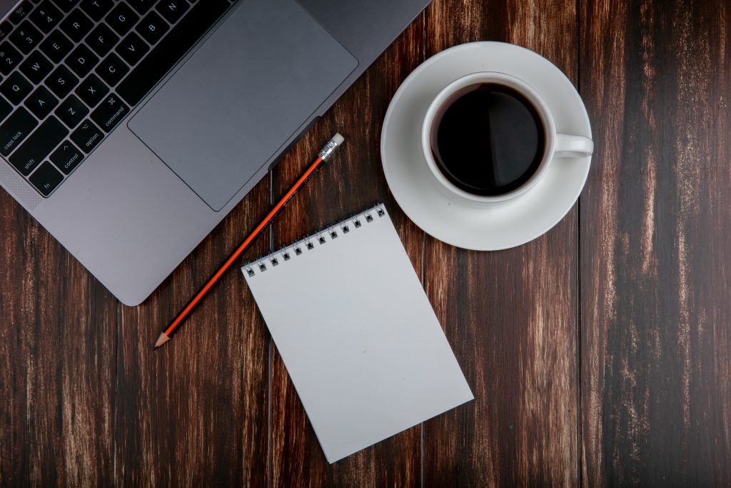 top-view-copy-space-cup-tea-with-notebook-pencil-notebook-wooden-background
